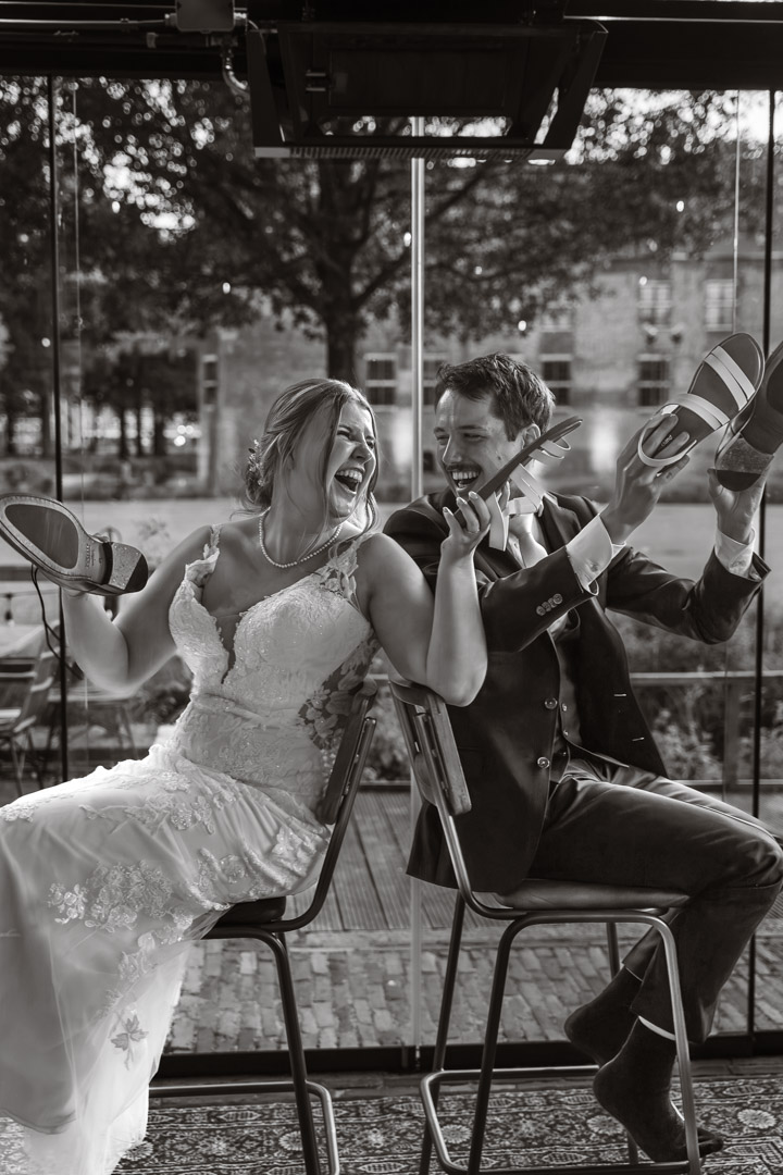 trouwfotografie in een serre, bruidspaar doet het schoenenspel