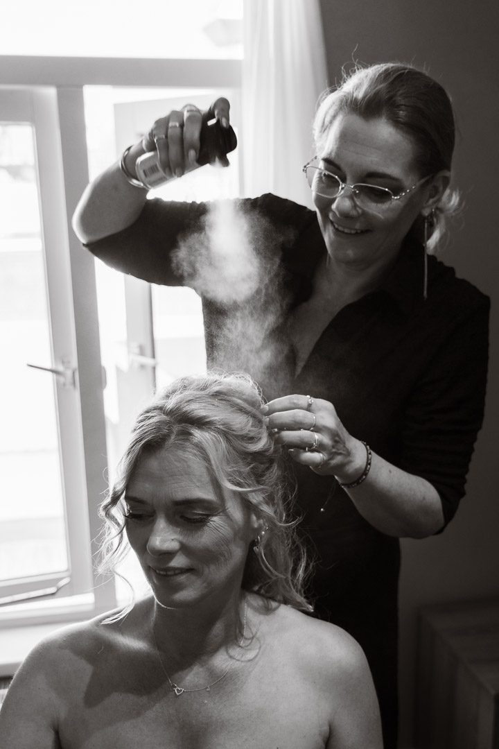 kapster doet het haar van de bruid